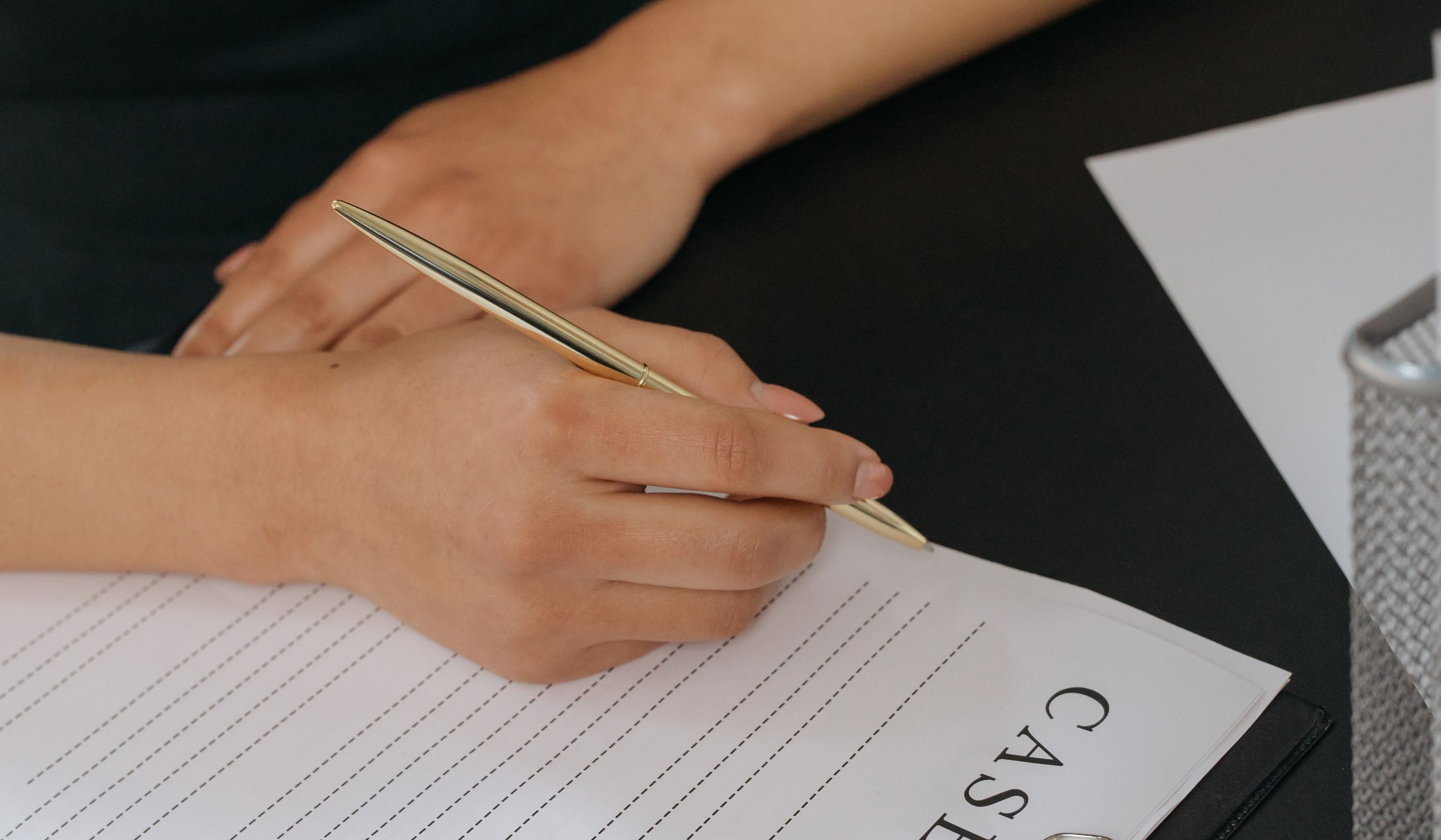 A hand holding a pen over a ruled document, mid-review