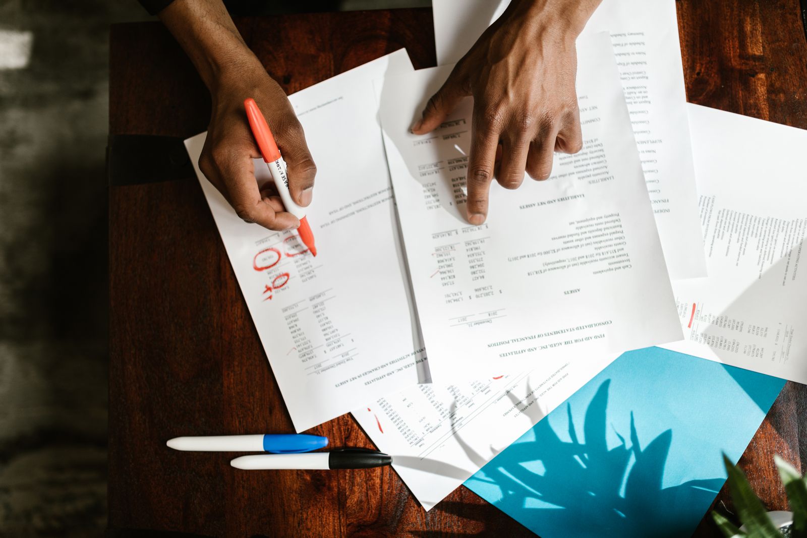 Hands marking up a financial statement with a pen, figures circled