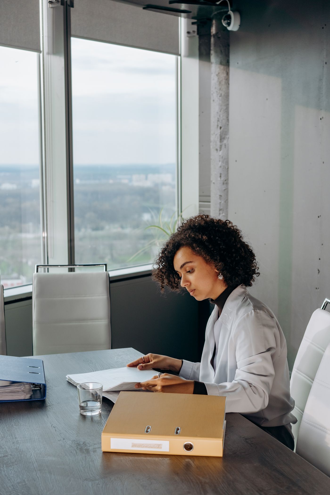 Nadia working at a desk by the window with a folder and calculator